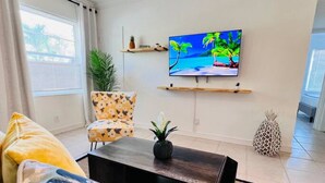 A living room with a sofa, armchair, coffee table, and a TV on a wall. - Cozy 2 BR Condo - 7 Min from Fort Lauderdale Beach (Fort Lauderdale)
