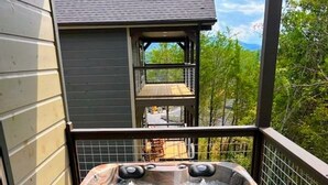 Ein Whirlpool auf einer Holzterrasse mit Blick auf ein Haus und Bäume im Hintergrund.