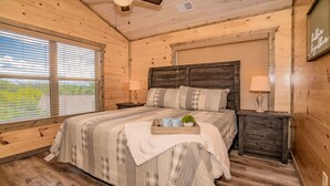 Ein gemütliches Schlafzimmer mit einem großen Bett, einem Holzkopfende und einem Fenster mit Jalousien.