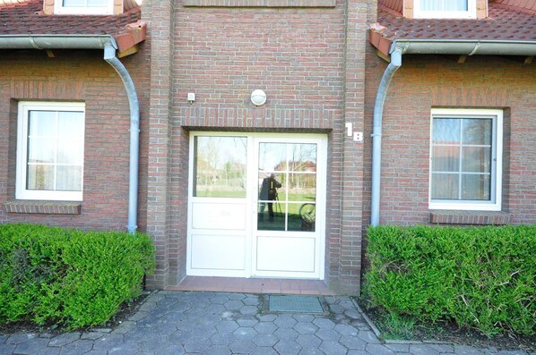 A brick building with a central door, two windows on either side, and a small overhang above the door.