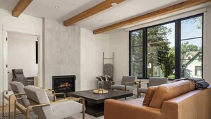 Uma sala de estar moderna com lareira, sofá de couro e uma grande janela com vista para o exterior.