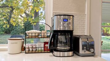 Una encimera de cocina con cafetera, tostadora y una taza de café.