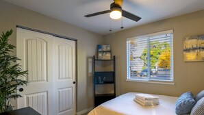 A bedroom with a bed, a ceiling fan, a window with blinds, a bookshelf, and a door. - Denver 3bed/2 bath with spacious backyard (Arvada)