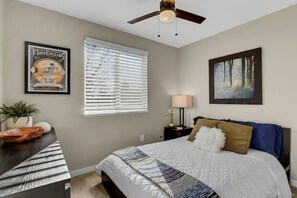 Relax in comfort with a large bed, ceiling fan, and natural light pouring in through the window.