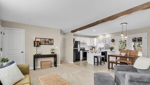 A modern living room with a sofa, ottoman, and a dining area with a table and chairs. - Denver 3bed/2 bath with spacious backyard (Arvada)