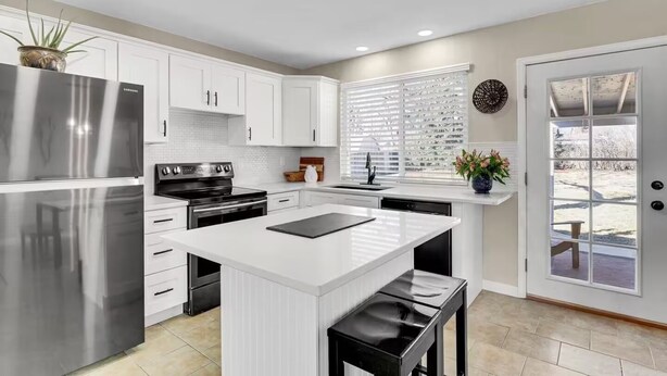 A modern kitchen with white cabinetry, stainless steel appliances, and a large island. - Denver 3bed/2 bath with spacious backyard (Arvada)