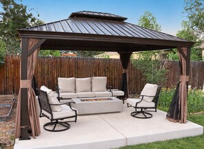 A covered patio with a metal roof, beige cushioned seating, and a fire pit. - Denver 3bed/2 bath with spacious backyard (Arvada)