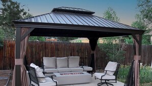 A covered patio with a metal roof, cushioned seating, and a fire pit. - Denver 3bed/2 bath with spacious backyard (Arvada)