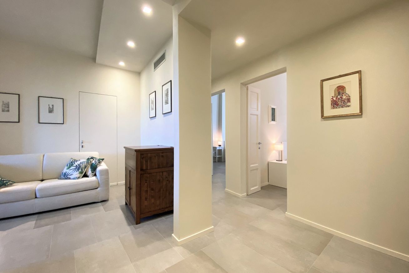 A modern living room with a white sofa, a wooden cabinet, and framed pictures on the walls.