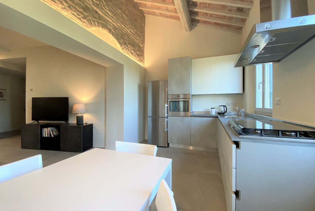A modern kitchen with white cabinets, a stainless steel range hood, and a built-in oven.
