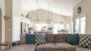 A spacious living room with a large sectional sofa, a wooden coffee table, and a kitchen in the background. - Cave Creek Gem: Heated Pool, Sleeps 8 (Cave Creek)