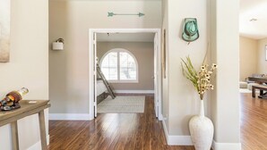 A hallway with wooden flooring, a white door, and a staircase leading to an upper level. - Cave Creek Gem: Heated Pool, Sleeps 8 (Cave Creek)