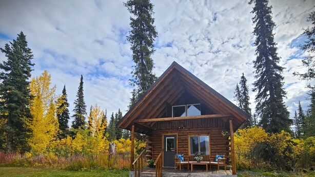 Une cabane en bois avec une véranda, un escalier et une table de pique-nique.