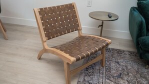 Ein Holzstuhl mit geflochtenem Rücken und Sitzfläche, auf einem hellen Holzboden platziert.