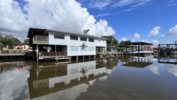 A waterfront house with a dock, a covered area, and a reflection in the water.