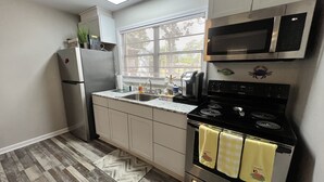 A compact kitchen with a refrigerator, microwave, stove, and sink.