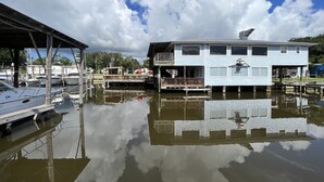 A waterfront property with a dock, a covered area, and a two-story house with a balcony.