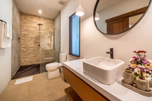Ein modernes Badezimmer mit Steinwand, Waschbecken in Weiß und einem Spiegel.