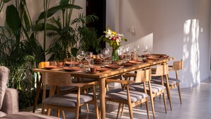 A dining area with a long wooden table set for six, surrounded by chairs with cushioned seats. - Walking distance from Berawa Beach - 4 BDR (Kecamatan Kuta Selatan)