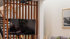 A modern living room with a wooden partition, a flat-screen TV, a sofa, a coffee table, and a dining area with chairs. - Walking distance from Berawa Beach - 4 BDR (Kecamatan Kuta Selatan)