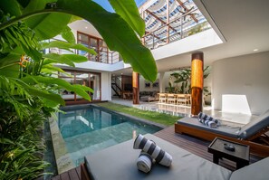 A modern house with a glass-bottomed pool, wooden deck, and lounge area with sun loungers. - Walking distance from Berawa Beach - 4 BDR (Kecamatan Kuta Selatan)