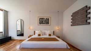 A modern hotel room with a large bed, wooden flooring, a large mirror, and a wall art piece. - Walking distance from Berawa Beach - 4 BDR (Kecamatan Kuta Selatan)