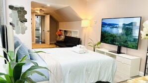 A modern hotel room with a large bed, a flat-screen TV, a desk, and a seating area.