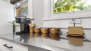 Un comptoir de cuisine avec une machine à café, des bols en bois et une boîte à suggestions.