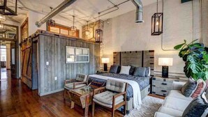 A spacious living area with a large bed, two sofas, and a wooden accent wall.