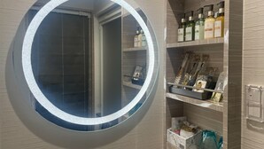 A bathroom with a round mirror, shelves with toiletries, and a marble sink. - Hotel DIAMOND (Tokyo)