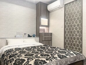 A modern hotel room with a bed, a nightstand, a mirror, and an air conditioning unit. - Hotel DIAMOND (Tokyo)