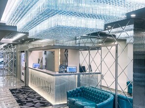 A reception area with a modern design, featuring a glass partition, a reception desk, and a blue upholstered sofa. - Hotel DIAMOND (Tokyo)