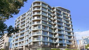 Un edificio de varios pisos con fachada curva, balcones y ventanas amplias.