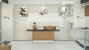 Un baño moderno con tocador de madera, cabina de ducha de vidrio y obras de arte en las paredes.