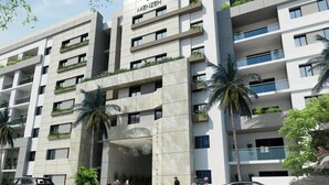 Un moderno edificio de varios pisos con balcones, palmeras y cielo despejado.