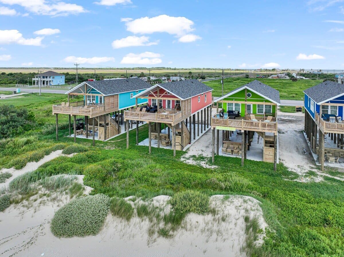 A beachfront property with multiple wooden structures featuring elevated decks and outdoor seating areas.