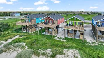 A beachfront property with multiple wooden structures featuring elevated decks and outdoor seating areas.