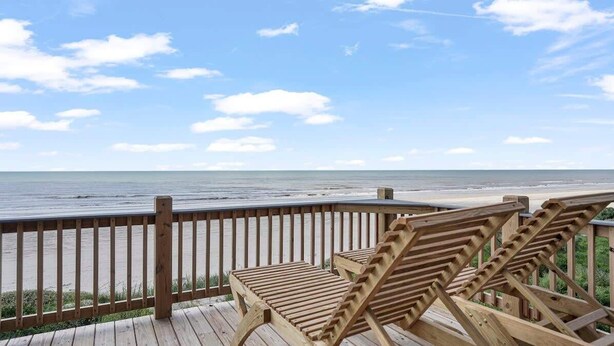 Terraza de madera con dos sillones de descanso con vista a la playa.