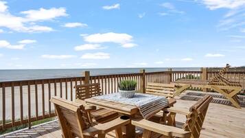 Een houten terras met een tafel en stoelen, met uitzicht op zee.