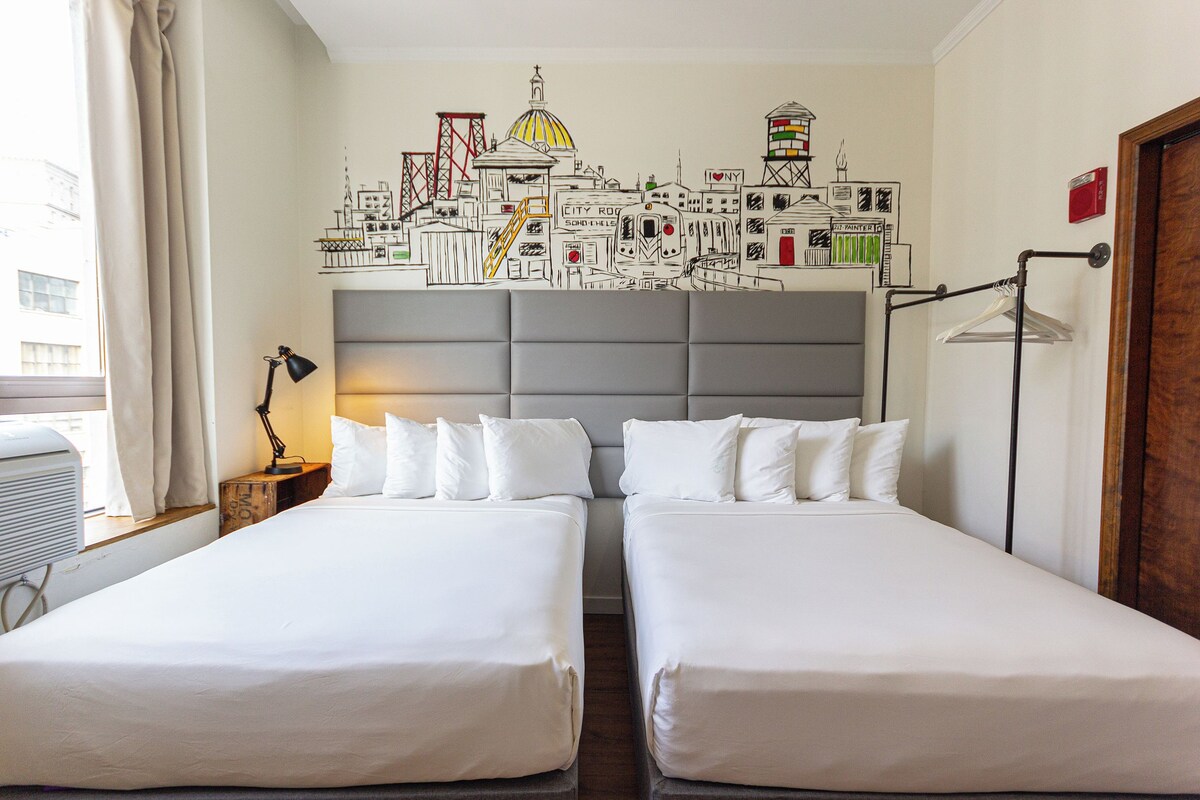 A hotel room with two beds, a cityscape mural, a hanging light, and a window with curtains.