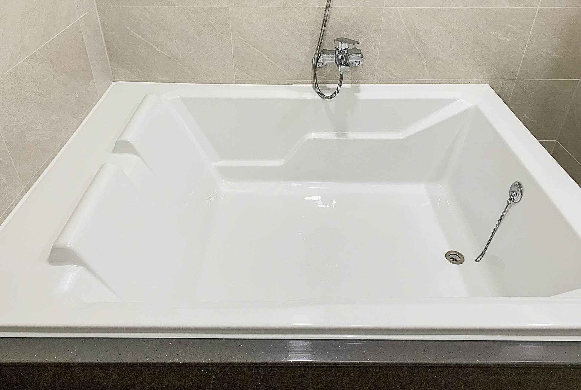 Une baignoire blanche avec un pommeau de douche et un drain.