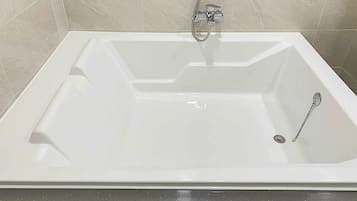 A white bathtub with a showerhead and a drain.