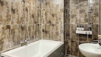 A bathroom with a bathtub, a shower, and a sink.