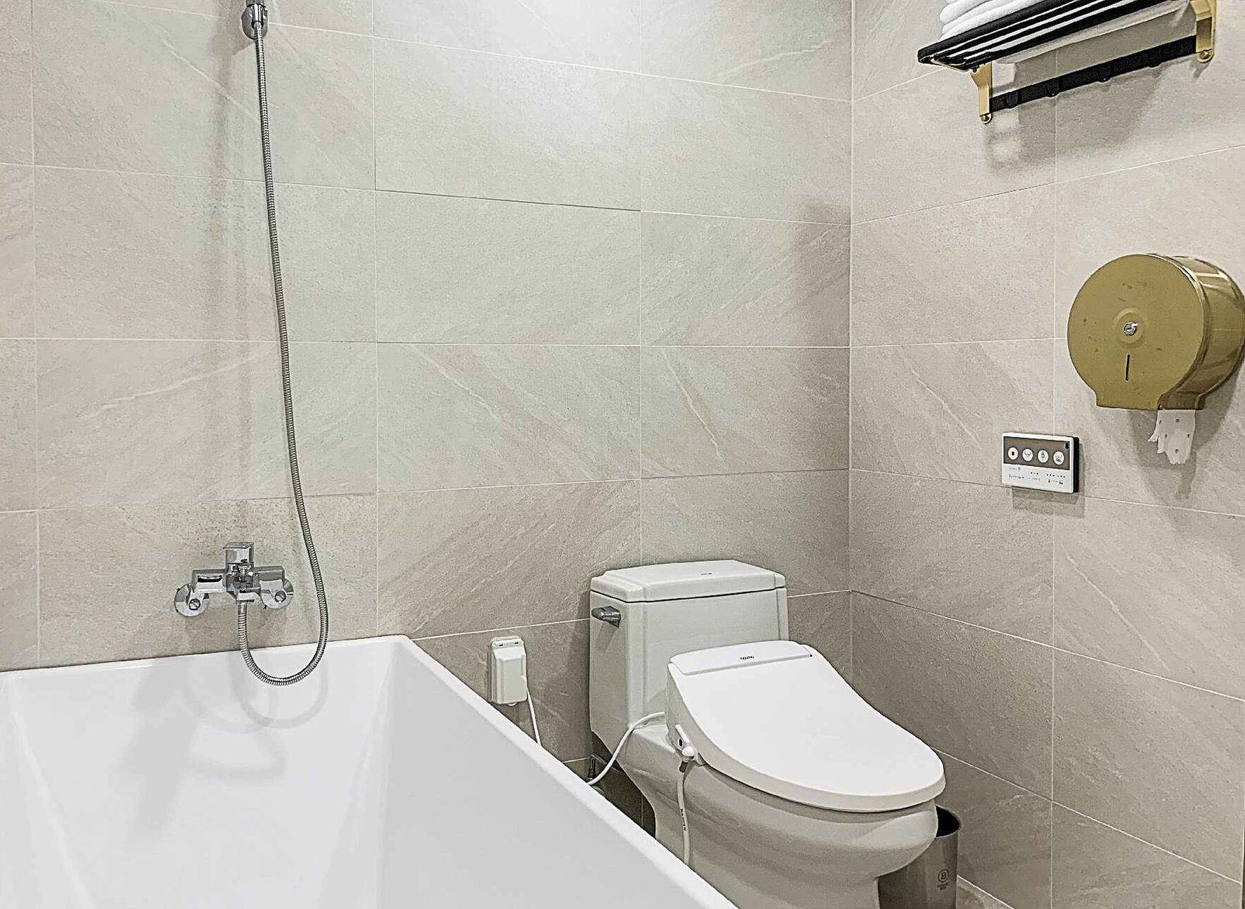 Un baño con bañera, inodoro y dispensador de toallas.