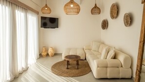 A modern living room with a beige sofa, a round coffee table, and a TV mounted on the wall. - Villa Casa Cielo by OriVista (Canggu)
