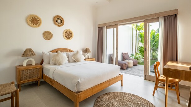 A bedroom with a wooden bed, bedside tables, a desk, and a view of the outdoors. - Villa Casa Cielo by OriVista (Canggu)