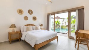 A bedroom with a wooden bed, two bedside tables, a wooden desk, and a large sliding glass door leading to a pool. - Villa Casa Cielo by OriVista (Canggu)