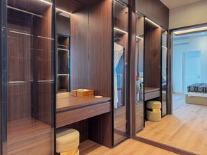 A modern walk-in closet with mirrored doors, wooden shelving, and a bench. - Villa Louis Legian by Nagisa Bali (Legian)