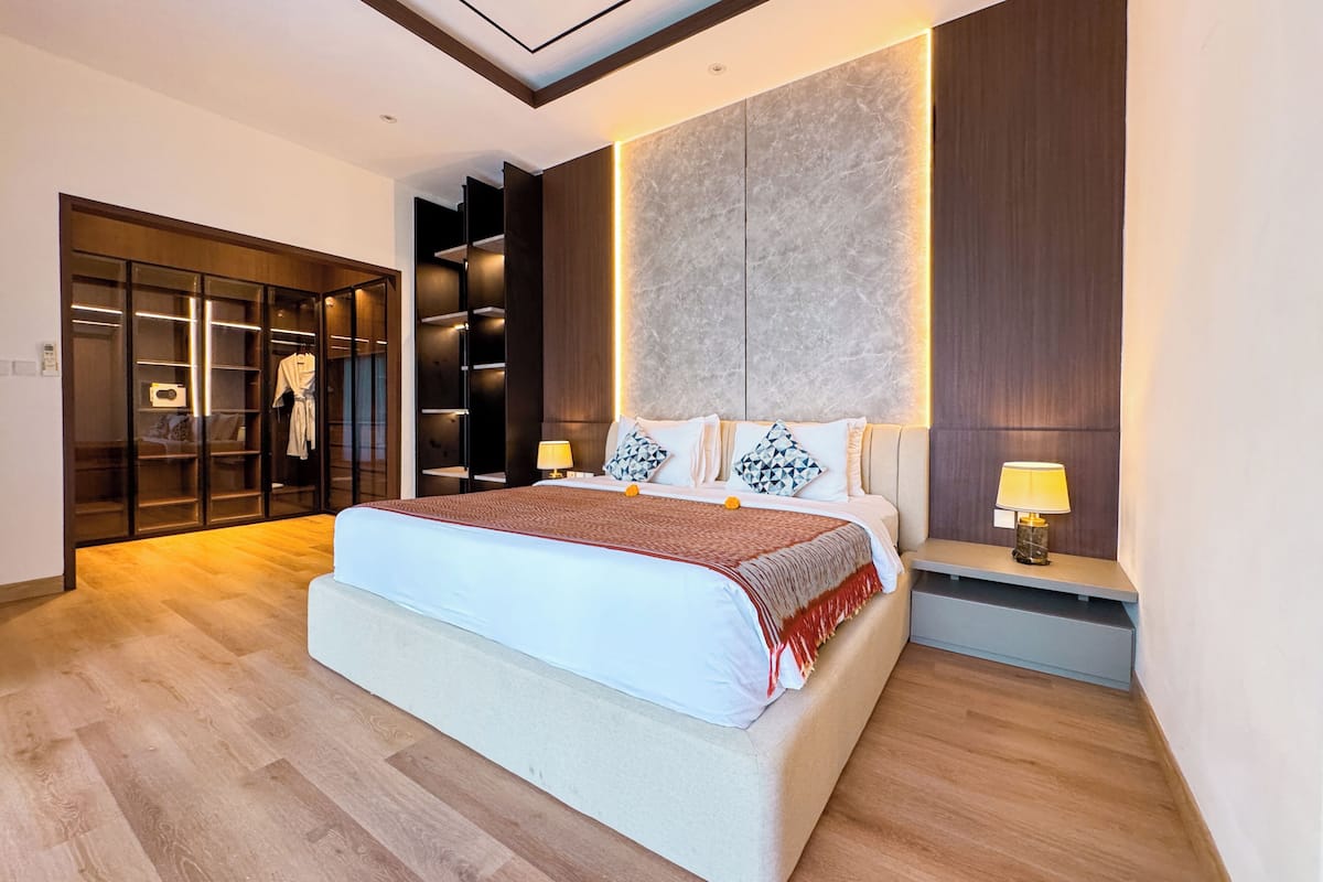 Un dormitorio moderno con una cama grande, armario empotrado y una mesita de noche con lámpara.