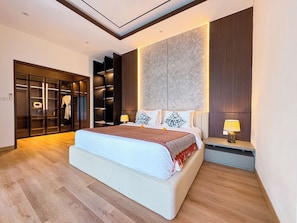 Ein modernes Schlafzimmer mit einem großen Bett, einem Einbauschrank und einem Nachttisch mit Lampe.